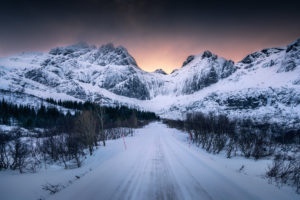 Norway, Lofoten, road in winter, sunset behind the mountains Norway, Lofoten, road in winter, sunset behind the mountains